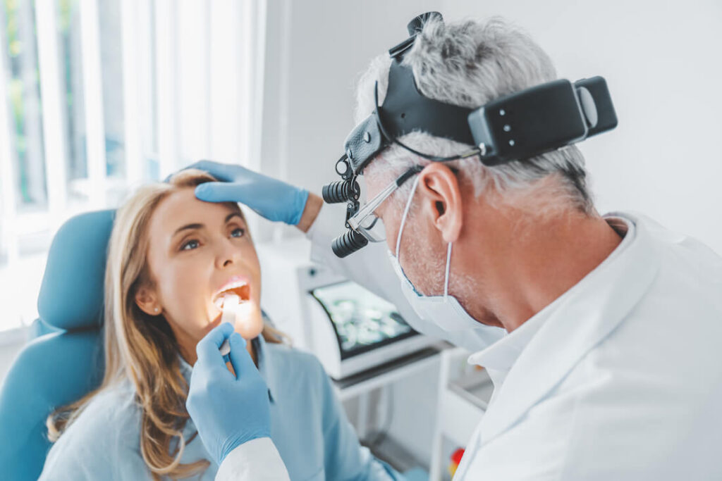Mature doctor checking woman's teeth - Dr. Lukas Pytlik